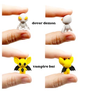 May include: Miniature figurines of a Dover Demon and a vampire bat. The Dover Demon is gray with yellow eyes, and the vampire bat is yellow with black wings. The text "dover demon" and "vampire bat" are printed on the image.
