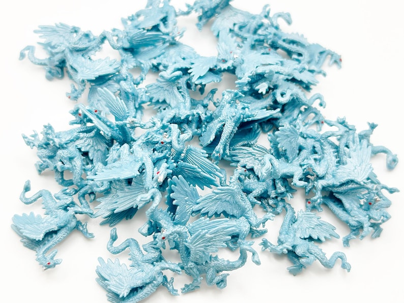 Peut inclure: Un grand groupe de figurines de dragons en plastique bleu clair. Les dragons ont des ailes, des queues et des yeux rouges.