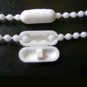 Peut inclure: Butée de chaîne en plastique blanc avec une petite languette en plastique blanc. La butée est conçue pour maintenir une chaîne de store ou de rideau.