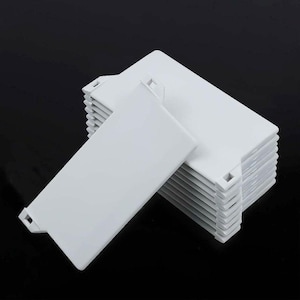 May include: A stack of ten white plastic tabs with a small hole in the top corner. The tabs are designed to be used as dividers or bookmarks.