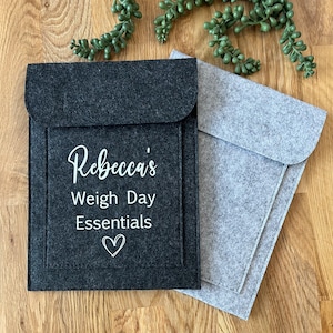 May include: Two felt pouches, one grey and one black. The black pouch has the text "Rebecca's Weigh Day Essentials" and a small heart.