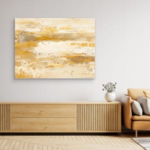 May include: A rectangular canvas wall art piece featuring an abstract painting with horizontal layers of textured paint in shades of cream, white, beige, and golden yellow, displaying a distressed, layered finish across the entire surface.