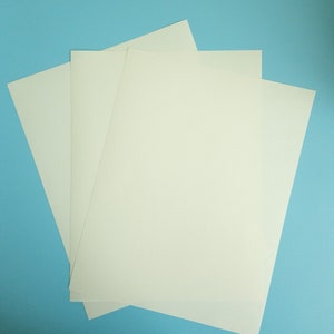 May include: Three sheets of white paper stacked on top of each other against a light blue background.