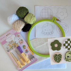 May include: A punch needle kit with green, white, and beige yarn, a green embroidery hoop, and a set of punch needles. The kit includes patterns for a flower, a monstera leaf, an octopus, and a checkered pattern.