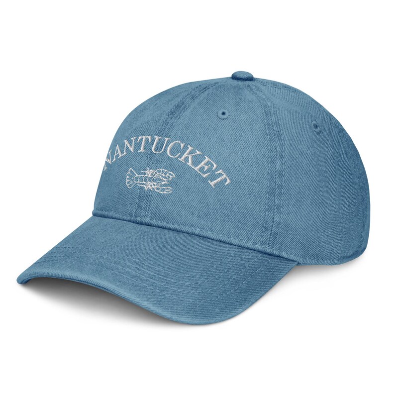 May include: A blue denim baseball cap with white embroidery that reads "NANTUCKET" with a white lobster design.