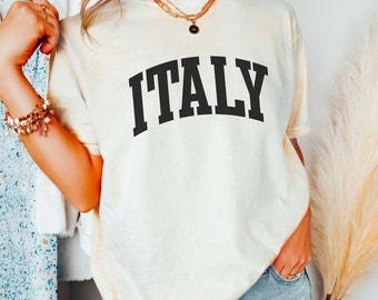 May include: A light yellow t-shirt with the word "ITALY" printed in black, in a collegiate font.