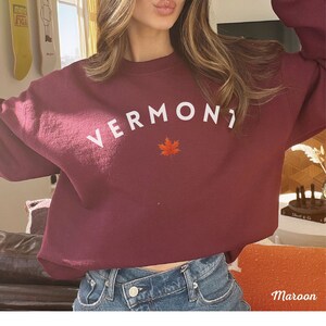 May include: A maroon sweatshirt with the word "VERMONT" in white lettering and a red maple leaf.