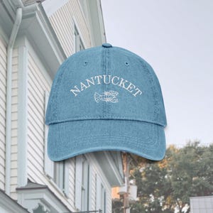 May include: A blue denim baseball cap with white embroidery that reads "NANTUCKET" with a lobster design.