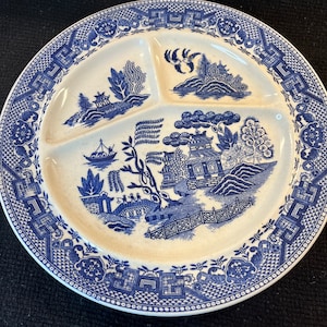 May include: A divided blue and white ceramic plate with a willow pattern design. The plate has three sections and a blue and white border.