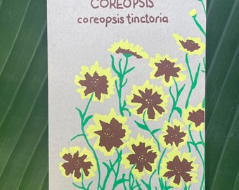 May include: A brown card with the text "COREOPSIS coreopsis tinctoria" printed in green. The card features a stylized illustration of yellow flowers with brown centers.