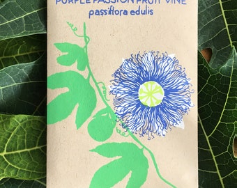 May include: A seed packet with the text "PURPLE PASSION FRUIT VINE passiflora edulis" in blue. The packet features a green illustration of a passion fruit flower and vine on a tan background. The flower is blue with a yellow center.
