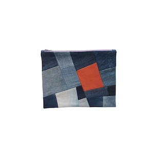 Könnte beinhalten: Eine blaue Jeans-Clutch mit Patchwork-Design. Die Clutch ist aus verschiedenen Blautönen von Jeans gefertigt und hat ein einzelnes orangefarbenes Quadrat in der Mitte.