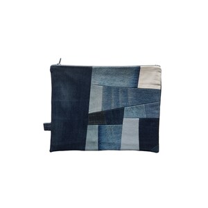 Könnte beinhalten: Eine blaue Jeans-Clutch aus Patchwork-Stoff. Die Clutch ist aus verschiedenen Blautönen von Jeans gefertigt und hat einen Reißverschluss.
