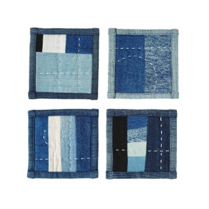 May include: Set of four blue denim coasters with different patchwork designs. Each coaster is made of various shades of blue denim and has white stitching.