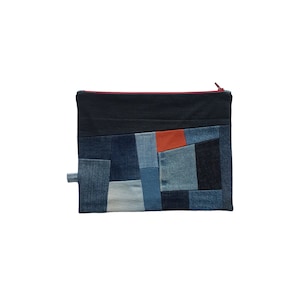 Könnte beinhalten: Eine Patchwork-Kosmetiktasche aus Jeans mit einem roten Reißverschluss und verschiedenen blauen Jeansstoffen.