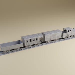 May include: A gray model train set with a locomotive, passenger car, and two freight cars on a track. The train is a miniature replica, likely for display or a hobby.