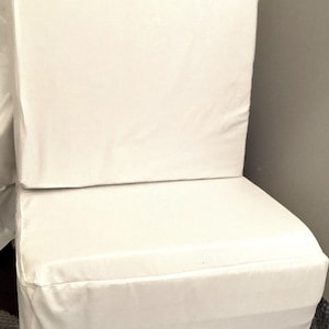 Puede incluir: Un colchón de espuma blanco de dos piezas con una funda con cremallera. El colchón está doblado por la mitad y está sobre una superficie blanca.