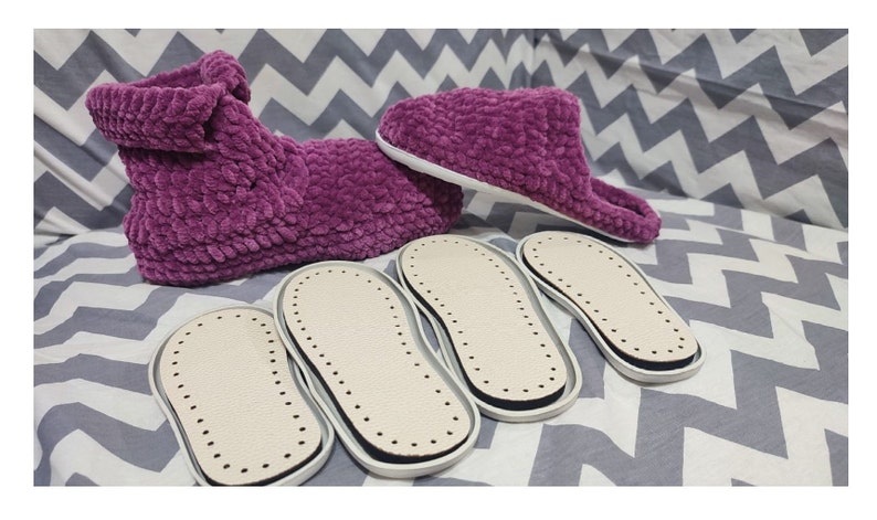 Puede incluir: Cuatro pares de suelas de zapatillas blancas y negras con una superficie texturizada. Tambi&eacute;n se muestran dos zapatillas de felpa morada.
