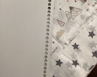 Könnte beinhalten: Ein weißer Stoff mit einem Muster aus grauen Bergen, Regenbögen, Sternen und Regentropfen. Der Stoff liegt neben einem weißen Lederkreis mit einer Reihe von Löchern am Rand. Der Text "POPLIN" ist auf dem Stoff sichtbar.