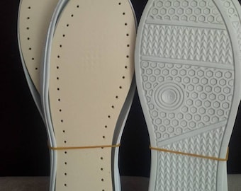 May include: Two pairs of white shoe insoles. One pair is made of a soft, beige material with small holes. The other pair is made of a white, textured material with a honeycomb pattern.