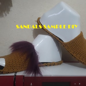 May include: A pair of brown crocheted sandals with a purple fuzzy trim. The sandals are displayed on a white mannequin. The text "SANDALS SAMPLE DIY" is visible in the image.