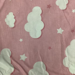 K&ouml;nnte beinhalten: Hellrosa Stoff mit einem sich wiederholenden Muster aus wei&szlig;en Wolken und Sternen. Die Wolken haben eine weiche, abgerundete Form, und die Sterne sind f&uuml;nfzackig. Der Stoff hat ein leicht strukturiertes Aussehen.