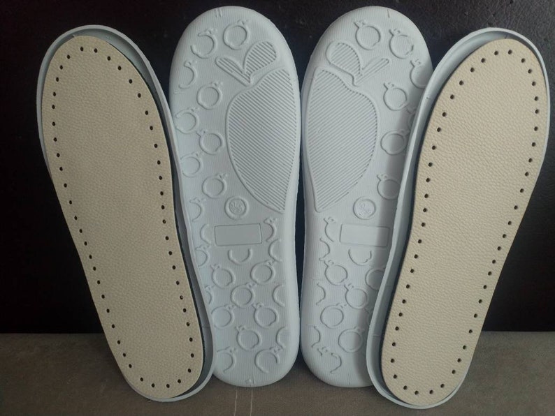 May include: Four shoe soles, two are white with a textured pattern and two are beige with a dotted pattern.