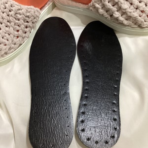May include: Two black leather insoles with a textured surface and small holes. The insoles are designed to provide comfort and support.