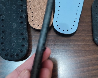 May include: Four leather insoles, one black, one brown, one light blue, and one black with a textured surface. The insoles are all oval shaped and have small holes around the edges.