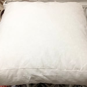 May include: A large, white, rectangular pillow with a smooth, soft surface. The pillow is made of a thick, durable fabric and has a simple, classic design.