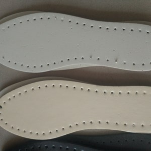 K&ouml;nnte beinhalten: Nahaufnahme von drei Schuhsohlen in den Farben Wei&szlig;, Beige und Schwarz. Jede Sohle hat eine Reihe von gleichm&auml;&szlig;ig verteilten L&ouml;chern am Umfang, die zum N&auml;hen bestimmt sind. Die Sohlen bestehen aus einem robusten Material, f&uuml;r Bastelarbeiten.