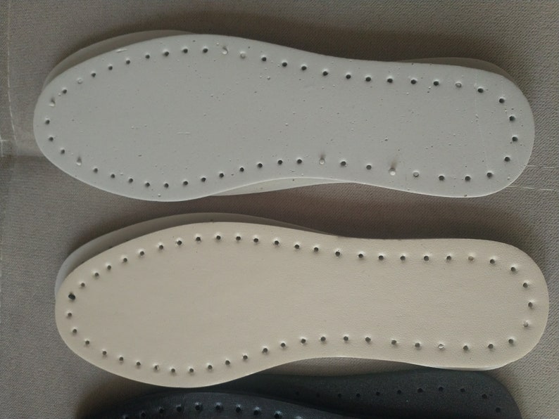K&ouml;nnte beinhalten: Nahaufnahme von drei Schuhsohlen in den Farben Wei&szlig;, Beige und Schwarz. Jede Sohle hat eine Reihe von gleichm&auml;&szlig;ig verteilten L&ouml;chern am Umfang, die zum N&auml;hen bestimmt sind. Die Sohlen bestehen aus einem robusten Material, f&uuml;r Bastelarbeiten.