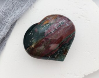 May include: A heart-shaped polished stone with a swirling pattern of red, green, and black.