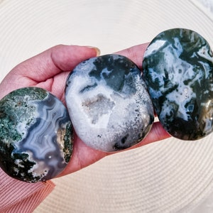 May include: Three green, white, and gray agate stones with a polished, smooth surface. The stones are oval shaped and have a natural, organic pattern.