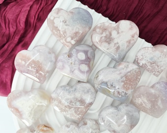 May include: A collection of heart-shaped pink and white agate stones. The stones have a natural, organic look with a variety of patterns and textures.