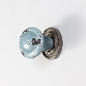May include: A light blue ceramic cabinet knob with a distressed finish and a silver metal base.
