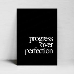 Op de afbeelding: Zwart-witte printbare wandkunst met de tekst "progress over perfection" in een modern lettertype.