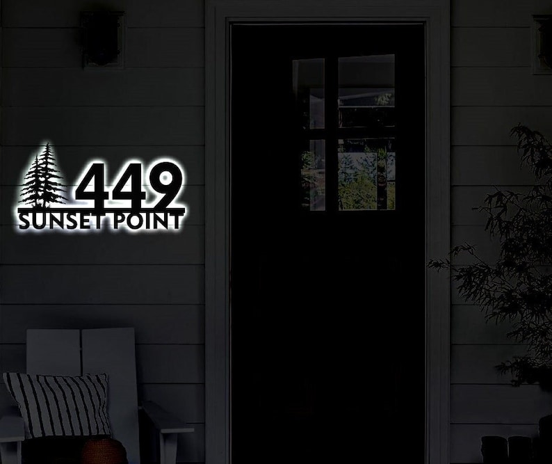 May include: A black metal house number sign with the number 449 and the words "Sunset Point" below. The sign is illuminated with white light.