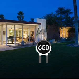 May include: A modern house with a white and black illuminated house number sign that reads "650".