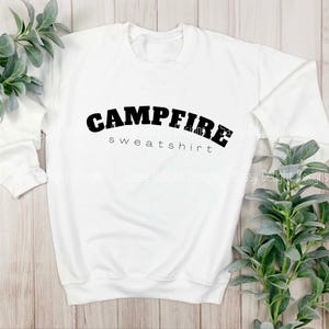 Puede incluir: Sudadera blanca con texto negro que dice "Campfire sweatshirt".