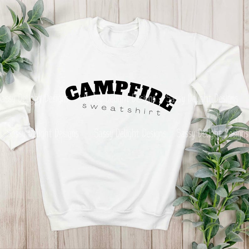 Puede incluir: Sudadera blanca con texto negro que dice "Campfire sweatshirt".