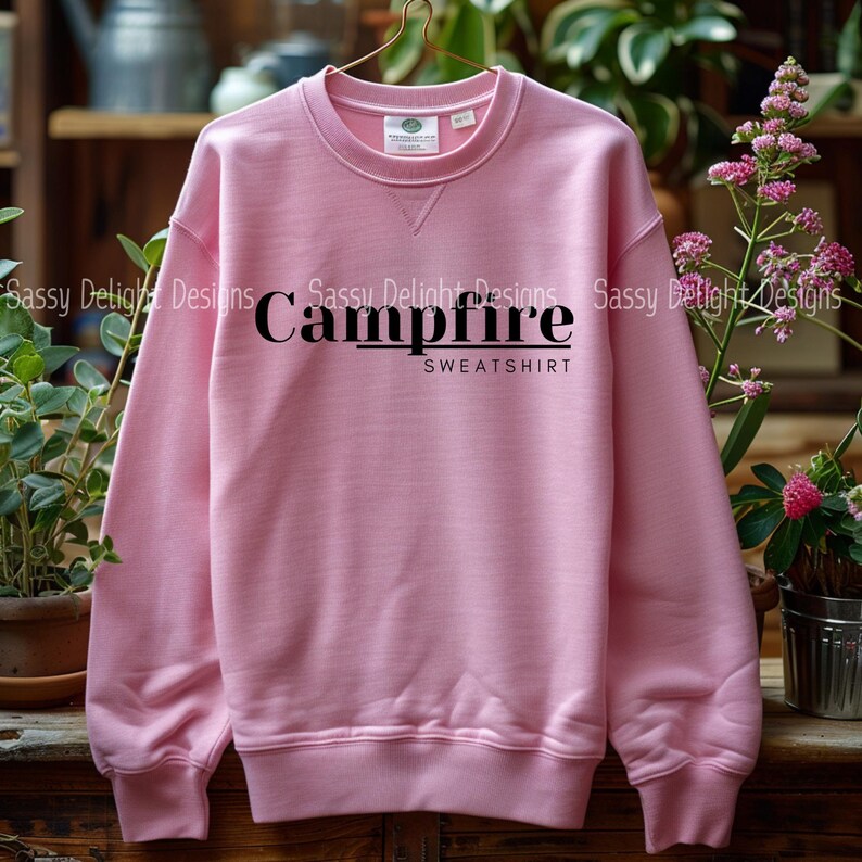 Puede incluir: Una sudadera rosa con el texto "Campfire Sweatshirt" impreso en negro.