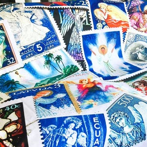 May include: A throw blanket with a design of vintage postage stamps depicting angels and religious figures. The stamps are in shades of blue, white, red, and green. The blanket is displayed on a grey surface.