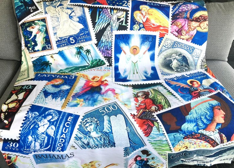 May include: A white cushion adorned with a collection of postage stamps depicting angels and religious figures. The stamps are in shades of blue, red, and yellow, with text including "ECUADOR" and "BAHAMAS".