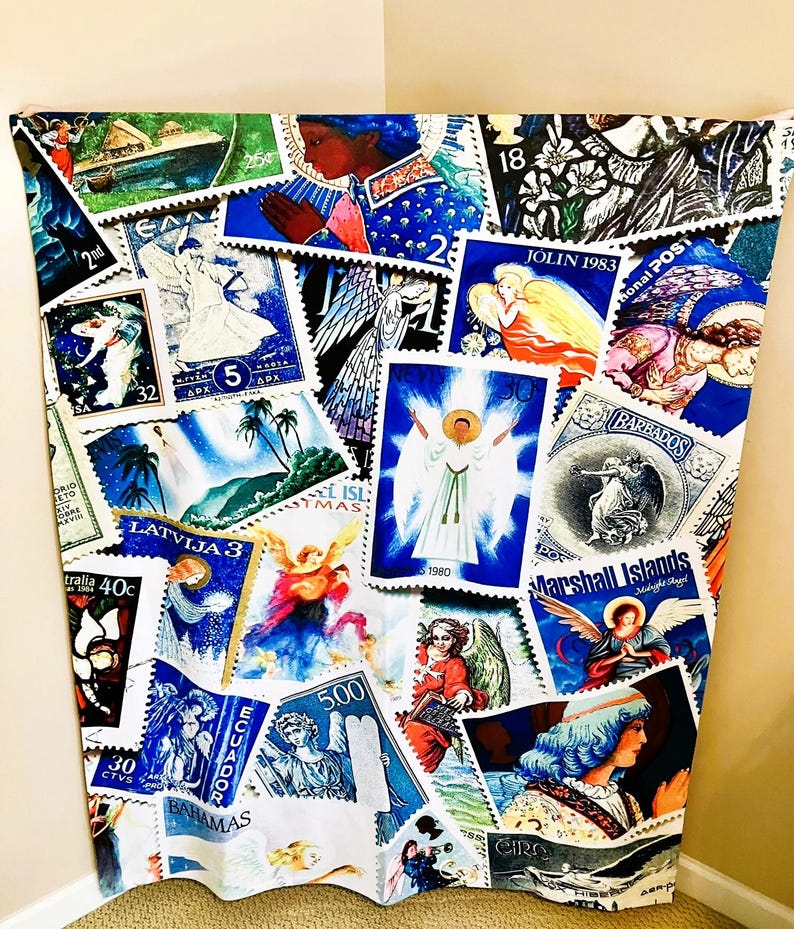 May include: A fabric panel adorned with a collage of vintage postage stamps. The stamps, in various sizes and shapes, depict angels, religious figures, and tropical scenes. Predominantly blue, white, and gold, the stamps are arranged on a white background.