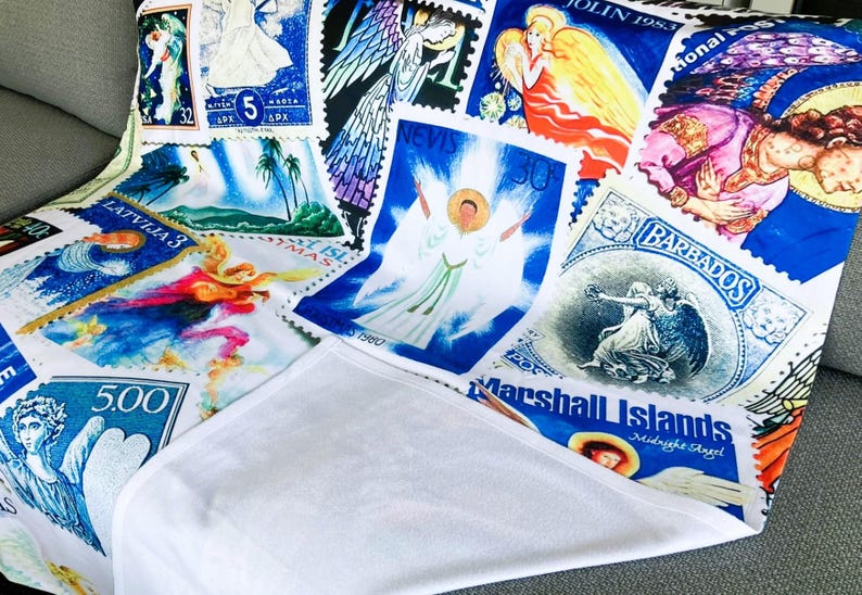 May include: A white blanket printed with a collection of vintage postage stamps. The stamps depict angels in various poses and colors, including blue, yellow, and red. Text includes "Barbados" and "Marshall Islands".