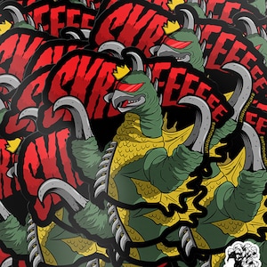 May include: Sticker sheet featuring a green monster with a crown, red visor, and large claws. The word "KREEK" is in red above the monster. The stickers have a white border and a skull logo in the bottom right corner. Text at the bottom warns of colour variations.