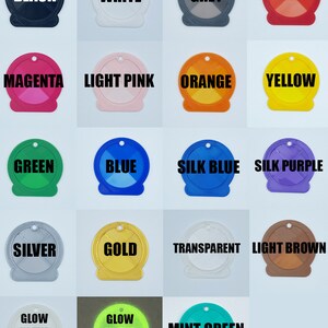 May include: A collection of 17 round plastic keychains in various colors, including black, white, grey, red, magenta, light pink, orange, yellow, green, blue, silk blue, silk purple, silver, gold, transparent, light brown, glow in the dark green, and mint green. Each keychain has a different color and features the color name printed in black text.