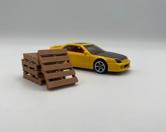 Puede incluir: Un coche de juguete amarillo con techo negro y una paleta de madera marrón.