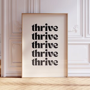 May include: A framed print with the word "thrive" repeated five times in a bold, black font on a white background.